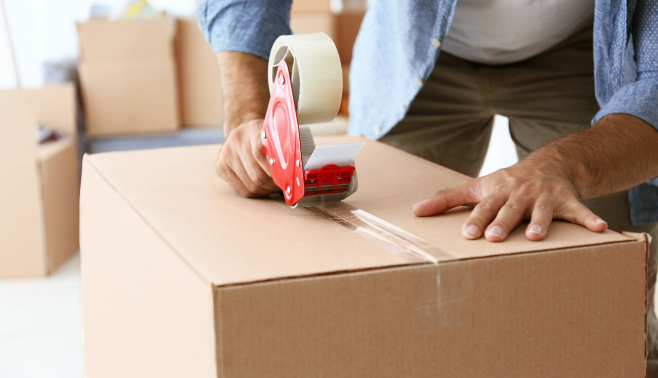 House,moving,concept.,closeup,of,man,packing,cardboard,box